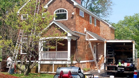 Preparing cedar house one side at a time. The right side is being brightened after cleaning where the front has just been cleaned.